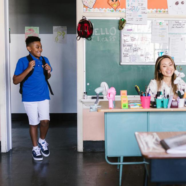 Child wearing a backpack walks into classroom.