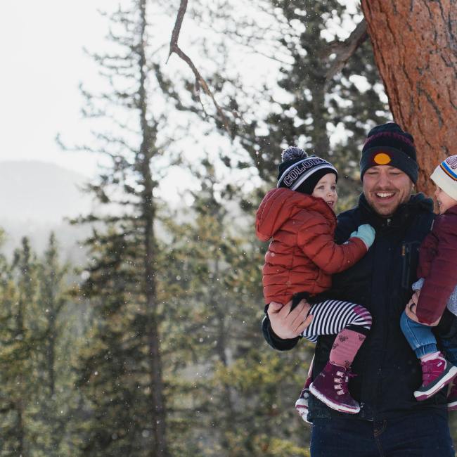Man holding children in winter woods.