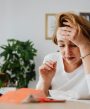 Woman at desk holding her head.